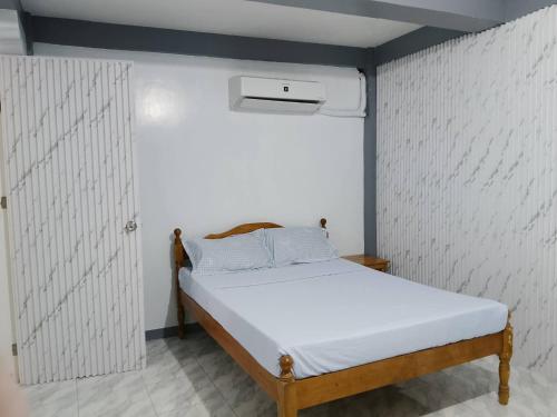 a small bed in a room with a white wall at Candava's Residence in Puerto Galera