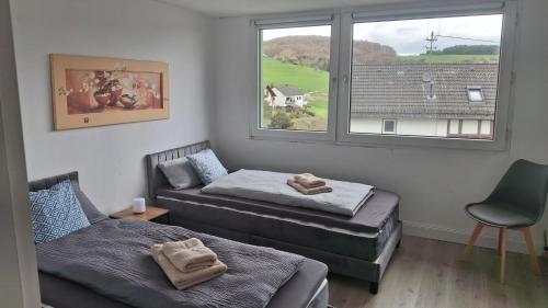 a room with two beds and a chair and a window at Ferienhaus am Ring in Wimbach