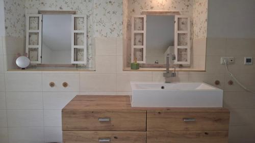 a bathroom with a white sink and two mirrors at Ferienhaus am Ring in Wimbach