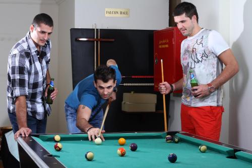 a group of men standing around a pool table at Cayam Hotel in Doha