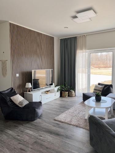 a living room with a tv and a couch and a table at Sõbra SPA Villa Haapsalu lähistel kaunis looduses in Nõmme