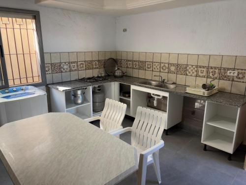 a kitchen with a table and two chairs in it at Villa blanche sfax in Sfax