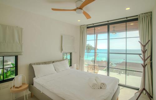 a bedroom with a bed with a view of the ocean at Fishman Beachfront Villas in Haad Pleayleam