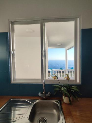 a kitchen sink with a window with a view of the ocean at Lucky Jack in Jardim do Mar