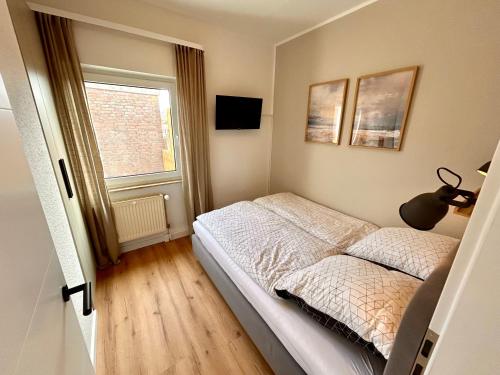 a small bedroom with a bed and a window at SielundMeer in Neuharlingersiel