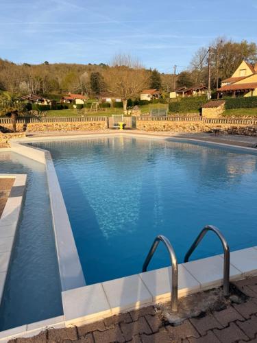 a large swimming pool with blue water at Gîte de la Bastide de Domme in Domme