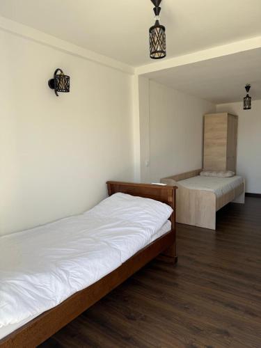 two beds in a room with white walls and wood floors at Stone Villa in Zagrađe