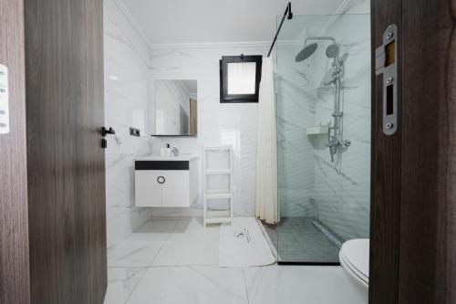 a white bathroom with a shower and a sink at Résidences Nador in Nador