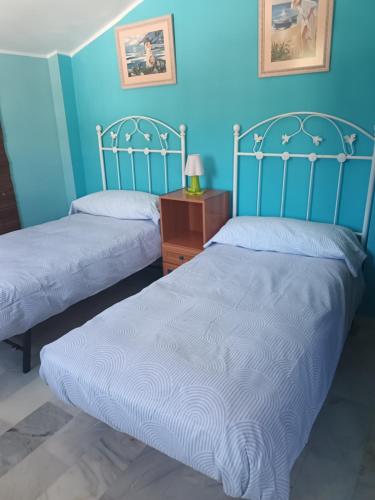 two beds in a room with blue walls at Apartamento Bahía Sol in Rincón de la Victoria
