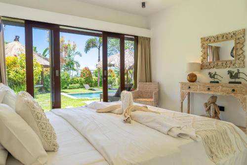 a bedroom with a large white bed with a fireplace at Villa Pascaline in Mengwi