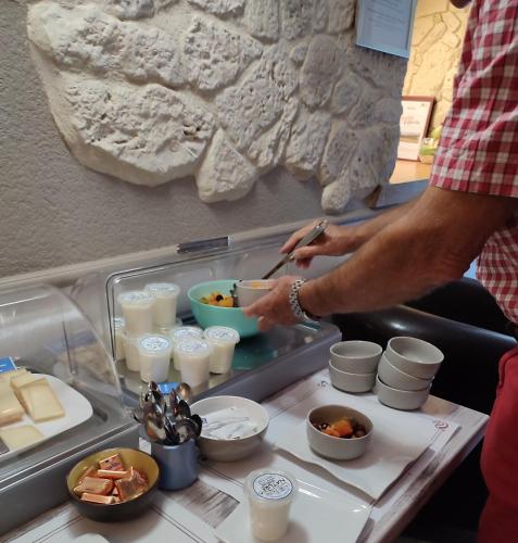 a man is preparing food in a buffet at Hostellerie Maleville, logis hôtel Pontet in Beynac-et-Cazenac