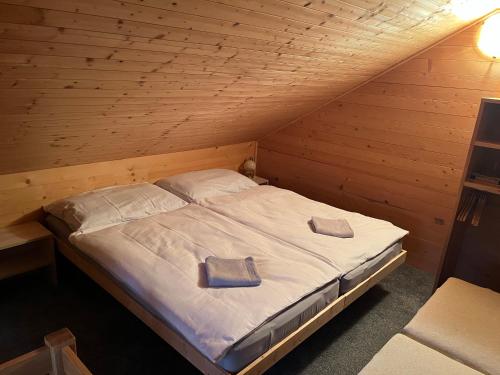 a bed in a wooden room with two pillows on it at Srub u Hadiny in Pelhřimov