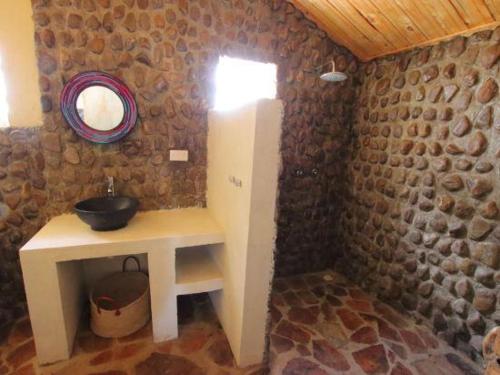 a bathroom with a sink and a stone wall at Odupoi Lodge in Maji Moto