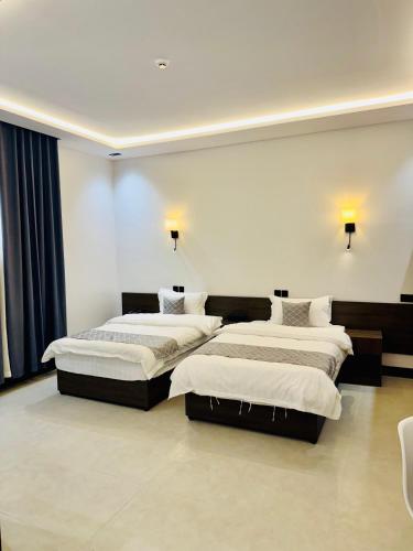 two beds in a room with two lamps on the wall at الشموخ بارك إن in Z̧alim