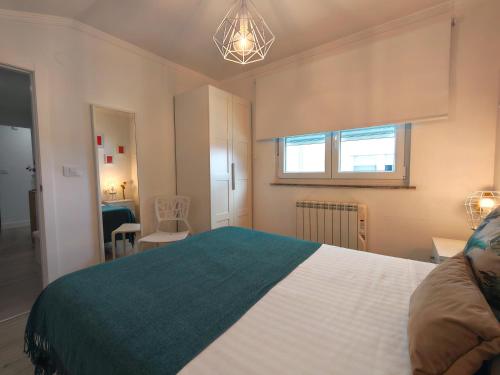 a bedroom with a large white bed and a window at Ático 32 in Lugo