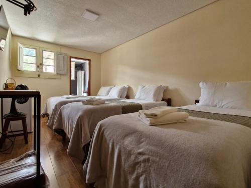 a room with three beds with white sheets at Pousada Memórias de Minas in Ouro Preto