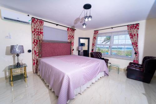 a bedroom with a large bed with a pink bedspread at Lagoon View Holiday Home in Montego Bay