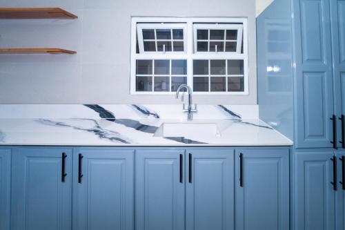 a blue kitchen with a sink and a window at Lagoon View Holiday Home in Montego Bay