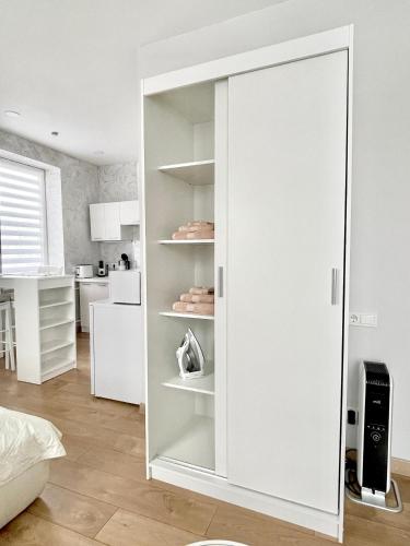 a white wardrobe in a room with a kitchen at Rami studio apartment in Panevėžys