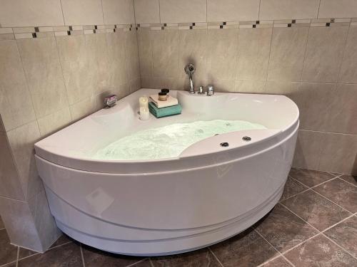 a white bath tub in a tiled bathroom at Eksklusiv tømmerhytte Spa Panoramautsikt in Aurdal