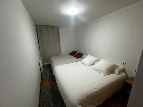 a small room with a bed with white sheets and pillows at Valdelinares 365 in Valdelinares