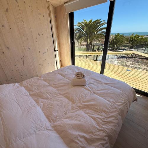 a large bed in a room with a large window at Costa Lodge Pichilemu in Pichilemu