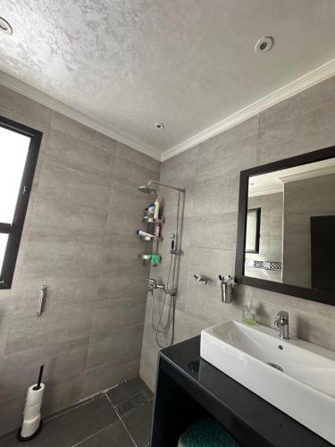 a bathroom with a sink and a shower with a mirror at Séjour chez habitant in Rabat