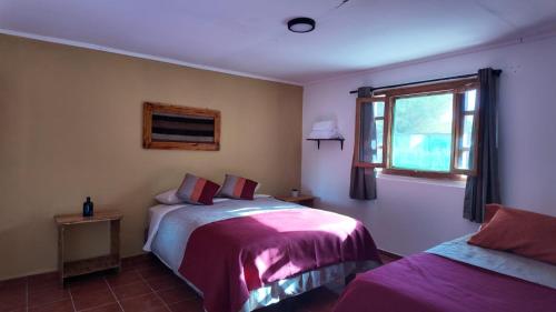 a bedroom with two beds and a window at El Rancho B&B in San Pedro de Atacama