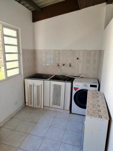 a kitchen with a washing machine and a sink at Recanto MJ in Campos do Jordão