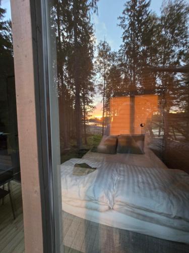 a bed is seen through a glass window at Seaside cottage with private beach & wood-fired sauna in Vörå, Finland in Oravais