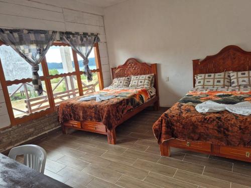 a bedroom with two beds and a table and a window at cabañas liquidambar in La Trinitaria