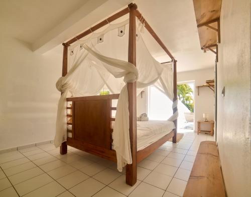 a bedroom with a canopy bed in a room at villa vue mer logements indépendants piscine privative in Grand-Bourg