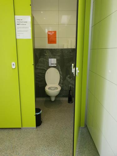 a bathroom with a white toilet in a stall at Pipowagen Doe Maar Roze in Bant