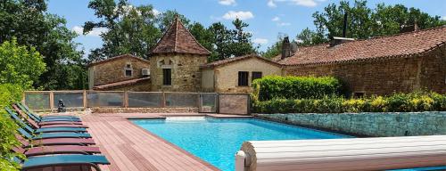 a swimming pool with lounge chairs in front of a house at Domaine du Cardou in Puy-lʼÉvêque