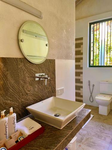 a bathroom with a sink and a mirror on the wall at Airport Coconut Villas Free Oneway Airport Pick Drop in Henpitagedara