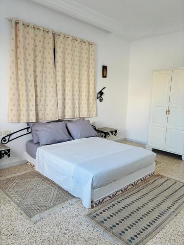 a bedroom with a white bed and a window at Jardins de Mezraya in Mezraya