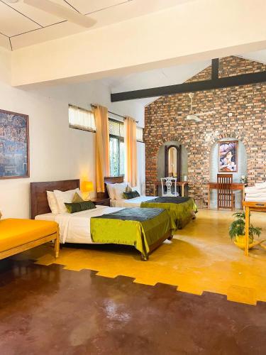 two beds in a room with a brick wall at Airport Coconut Villas Free Oneway Airport Pick Drop in Henpitagedara