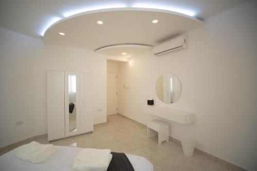 a white room with a bed and a mirror at Muscat Stays in Muscat
