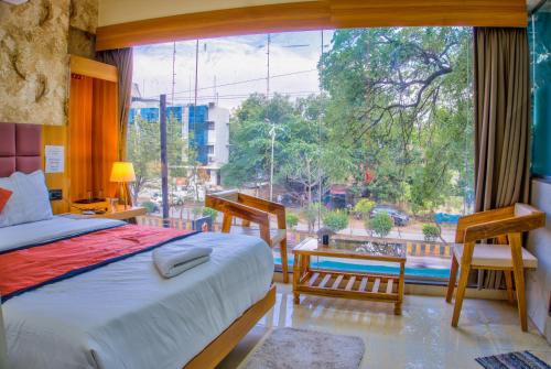 a bedroom with a bed and a large window at Hotel ShivSundar Executive in Aurangabad