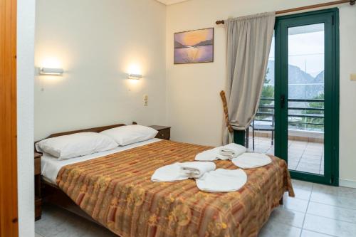 a hotel room with two beds and a balcony at Apolis hotel in Mouzaki