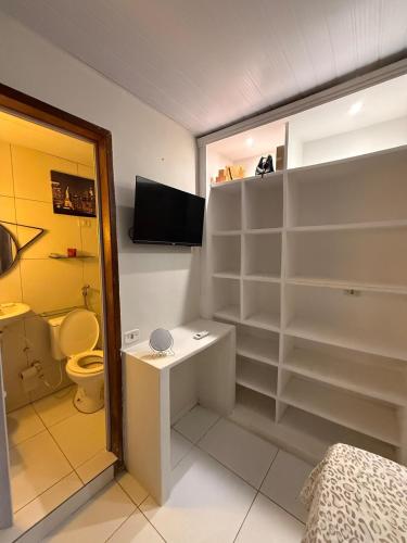 a bathroom with white shelves and a toilet and a television at Japaratinga CENTRO in Japaratinga