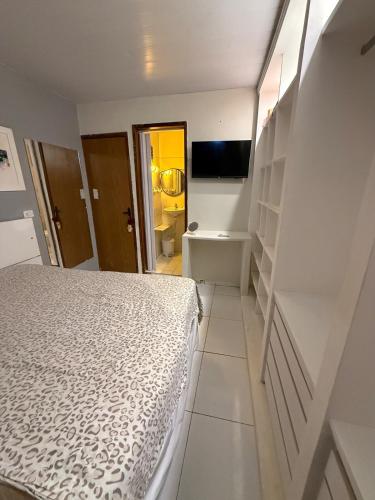 a white bedroom with a bed and a bathroom at Japaratinga CENTRO in Japaratinga