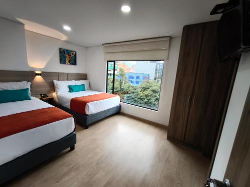 a hotel room with two beds and a window at Hotel Portal de los Andes in Bogotá