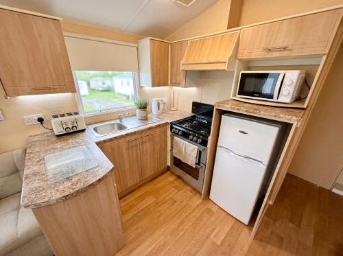 a small kitchen with a stove and a microwave at Blue Curlew in Scratby