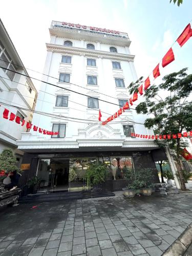 a large white building with red flags in front of it at hotel phúc khánh in An Dương