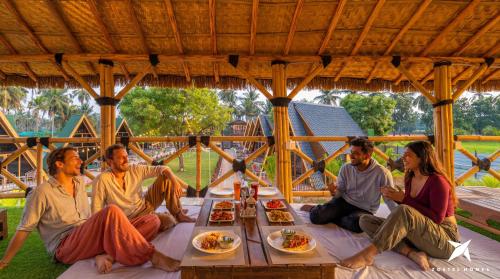 a group of people sitting around a table eating food at Zostel Homes Hampi in Hampi