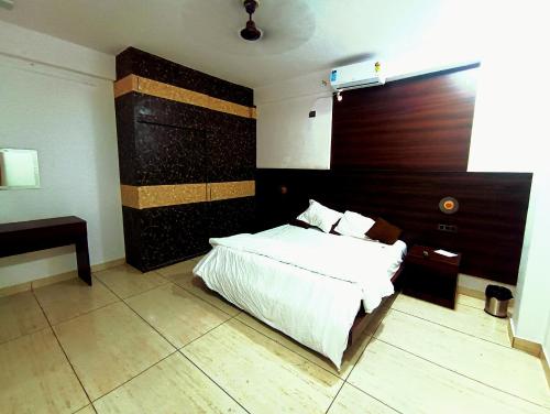 a bedroom with a white bed and a wooden headboard at Hotel Vivara in Lucknow