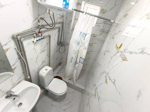 a white bathroom with a toilet and a sink at Infinity Hotel in Cholpon-Ata