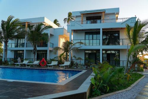 a building with a swimming pool and palm trees at Changarawe Hotel & Retreat in Pongwe