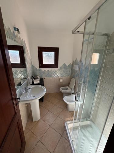 a bathroom with two toilets and a shower and a sink at Casetta Alamar in San Teodoro